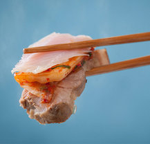 먹음직스러운 홍어,돼지고기,김치를 포개어 든 한젓가락